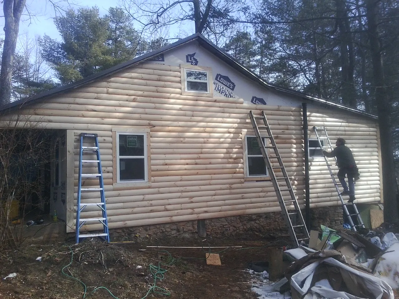 Ladders set against fresh log siding during an exterior remodel in Chatsworth