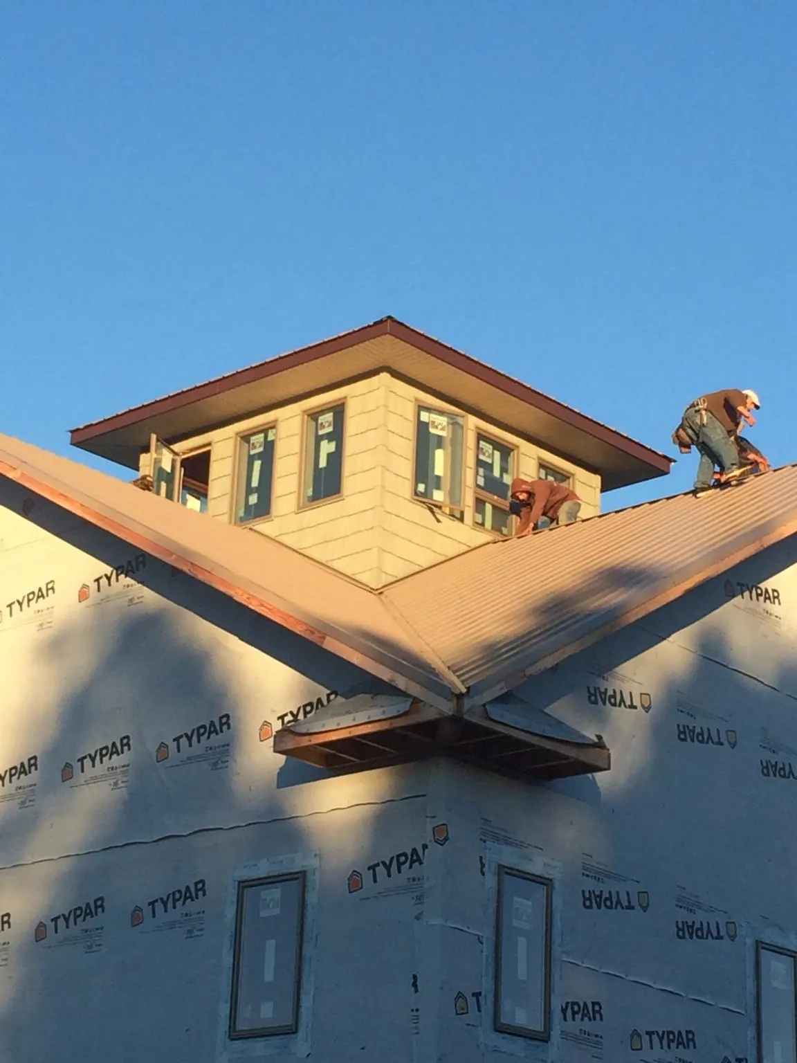 Roofers working around a rooftop cupola on a new metal roof at sunset — Roof Waterproofing in Chatsworth by Roofing Brothers